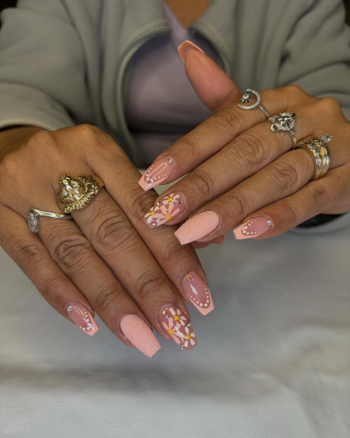 Uñas acrílicas solor crema, diseños diferentes, con una uña decorada con flores a pincel. 